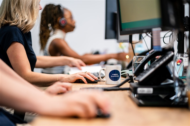 Women typing on computers in a bright office