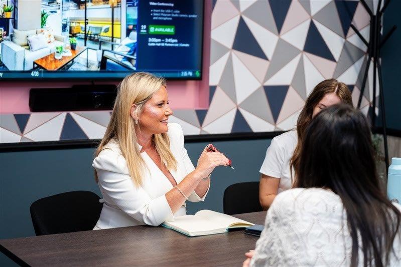 Women in a meeting, colourful background.
